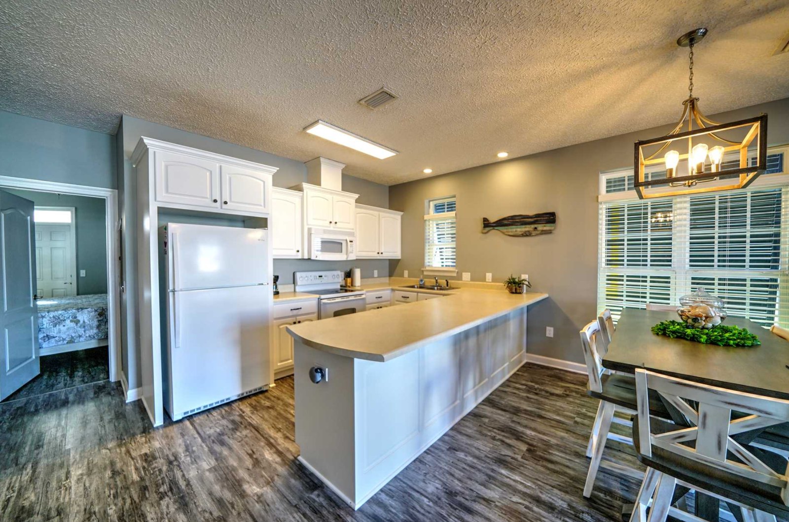 Kitchen with white cabinets, sand counters, and dining table