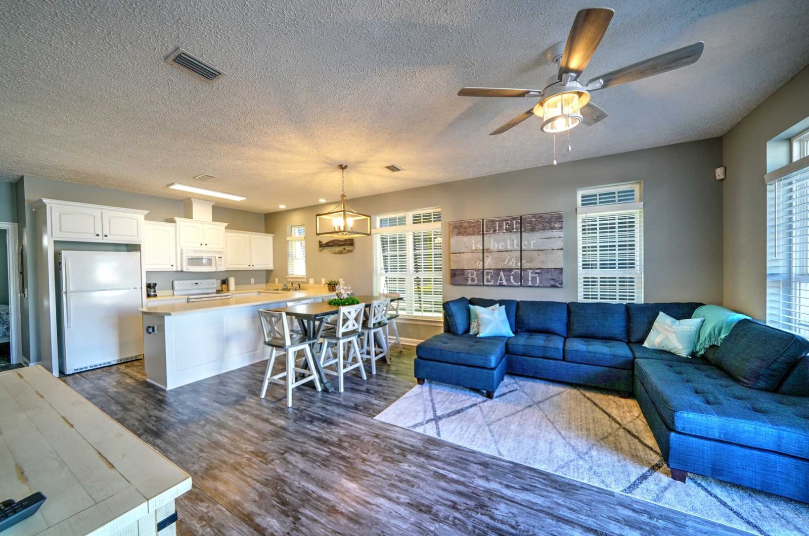 Open living room with navy sectional and beach wall art